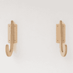 Two wooden hooks mounted on a white wall for hanging items.